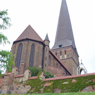 De Sint-Petruskerk (Duits: Petrikirche) is de oudste en met 117 meter de hoogste van de drie nog bestaande stadskerken in de hanzestad Rostock. De anderen zijn de Mariakerk en de Nicolaaskerk. Een vierde stadskerk, de Jacobikerk, werd in de Tweede Wereldoorlog verwoest en in 1960 ten slotte gesloopt. een godshuis opgericht. Het oudst bekende bewijs hiervoor dateert uit het jaar 1252. Het betrof een drieschepig gebouw, waarvan de muren deels uit graniet bestonden. Delen van deze eerste bouw zijn nog in de imposten van de zijschepen bewaard gebleven. In het midden van de 14e eeuw werd op de plaats van de voorganger de drieschepige basiliek in de voor het Oostzeegebied zo typerende stijl van de baksteengotiek gebouwd. Omstreeks het jaar 1500 kreeg de kerk een 127 meter hoge toren, die in 1543 door blikseminslag verwoest werd. Hierin meenden de nog overgebleven katholieken in de stad een straf Gods te zien. Tot 1578 vond herbouw van de toren plaats, nadat tussentijds de toren nog eens door een storm werd vernield. De toren had nu een hoogte van 117 meter en diende als oriëntatiepunt voor de omgeving, met name voor de schepen op de Oostzee. Ongunstige weersomstandigheden, waaronder een aantal stormen, lieten in de daaropvolgende eeuwen sporen na, die in 1902 tot een grondige restauratie leidden. In 1942 werd de Petruskerk tijdens een vier dagen durende luchtaanval van de Royal Air Force in de nacht van 26 op 27 april zwaar getroffen. De met koper beslagen torenspits brandde af. Het orgel, het barokke altaar, de renaissance-kansel alsook het enige epitaaf vielen ten prooi aan de vlammen. Daarentegen kon een middeleeuws bronzen doopvont uit 1512 worden gered. Eveneens wist men een kruiswegreliëf van Christus die wordt voorgeleid aan Pontius Pilatus te redden. Terwijl de gewelven van het middenschip en het zuidelijke zijschip het begaven, bleef het gewelf van het noordelijke zijschip bewaard. De wederopbouw van de kerk geschiedde bijzonder traag. De toren kreeg een nood dak en het middenschip werd van een 24 meter hoog vlak plafond voorzien. Ook werden de arcaden tussen het middenschip en de beide zijschepen dichtgemetseld en de muren wit gekalkt. Vooralsnog werd de torenspits niet teruggeplaatst. In 1994 kon in het kader van de stadsontwikkeling met middelen van de overheid, giften en steun van monumentenorganisaties de toren weer worden herplaatst. Op 45 meter hoogte werd een over 195 treden te bereiken uitzichtplatform toegevoegd. Bij helder weer is van daar uit een uitzicht tot Warnemünde en de Oostzee mogelijk. De kerk betreft een drieschepige basiliek met vier traveeën, in het westen afgesloten door een toren met spits, in het oosten door een polygonale koorafsluiting. Aan de noord- en zuidzijde van het koor bevinden zich kleine torentjes die met een spits worden bekroond. De open arcaden tussen de midden- en zijschepen werden na de oorlog dichtgemetseld. Hierdoor ontstaan drie praktische ruimten. Van het noordelijk zijschip is het kruisribgewelf bewaard gebleven. Het zuidelijk zijschip was te sterk verwoest om de oorspronkelijke constructie te herstellen. Dat laatste geldt ook voor het middenschip. De 17 meter hoge koorvensters met scènes uit het leven van de apostel Petrus werden in het begin van de jaren 1960 door Lothar Mannewitz (1930–2004) gemaakt.